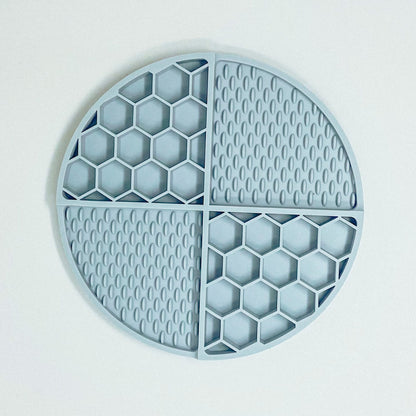 Pale blue silicone lick mat, separated into 4 sections. 2 sections are honeycomb shaped and 2 sections are licky texture.