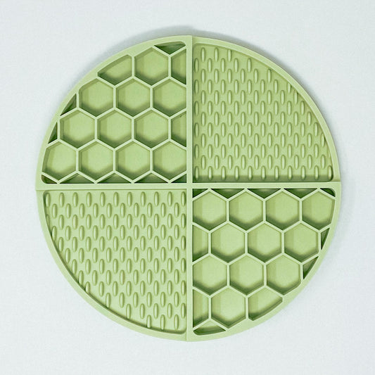 Sage green silicone lick mat, separated into 4 sections. 2 sections are honeycomb shaped and 2 sections are licky texture.
